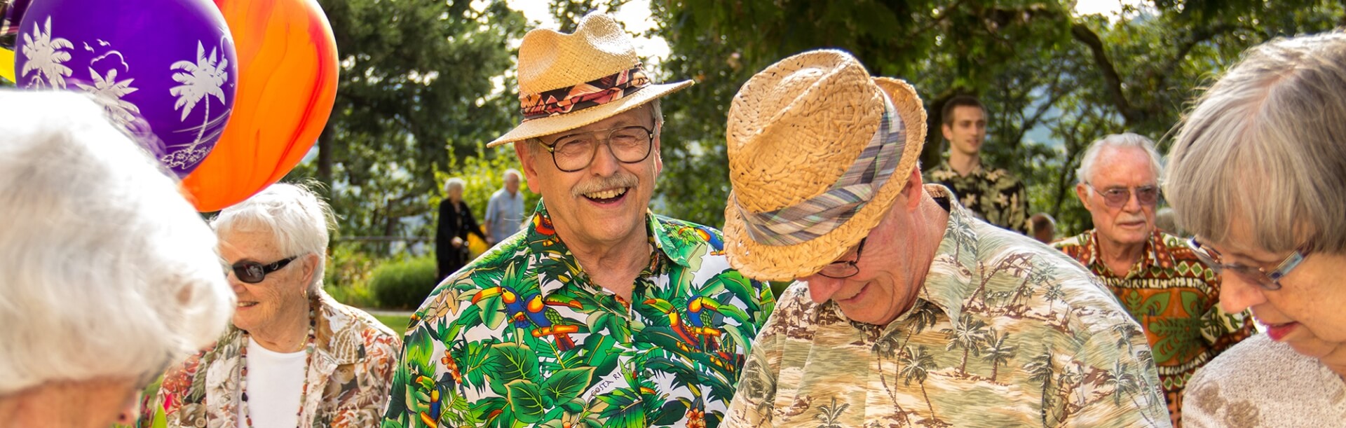 An outdoor Hawaiian-themed party showing several happy residents