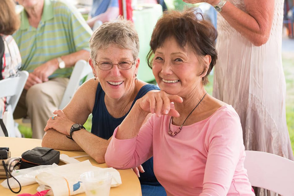 Two women smiling at camera attending a Willamette View outdoor party