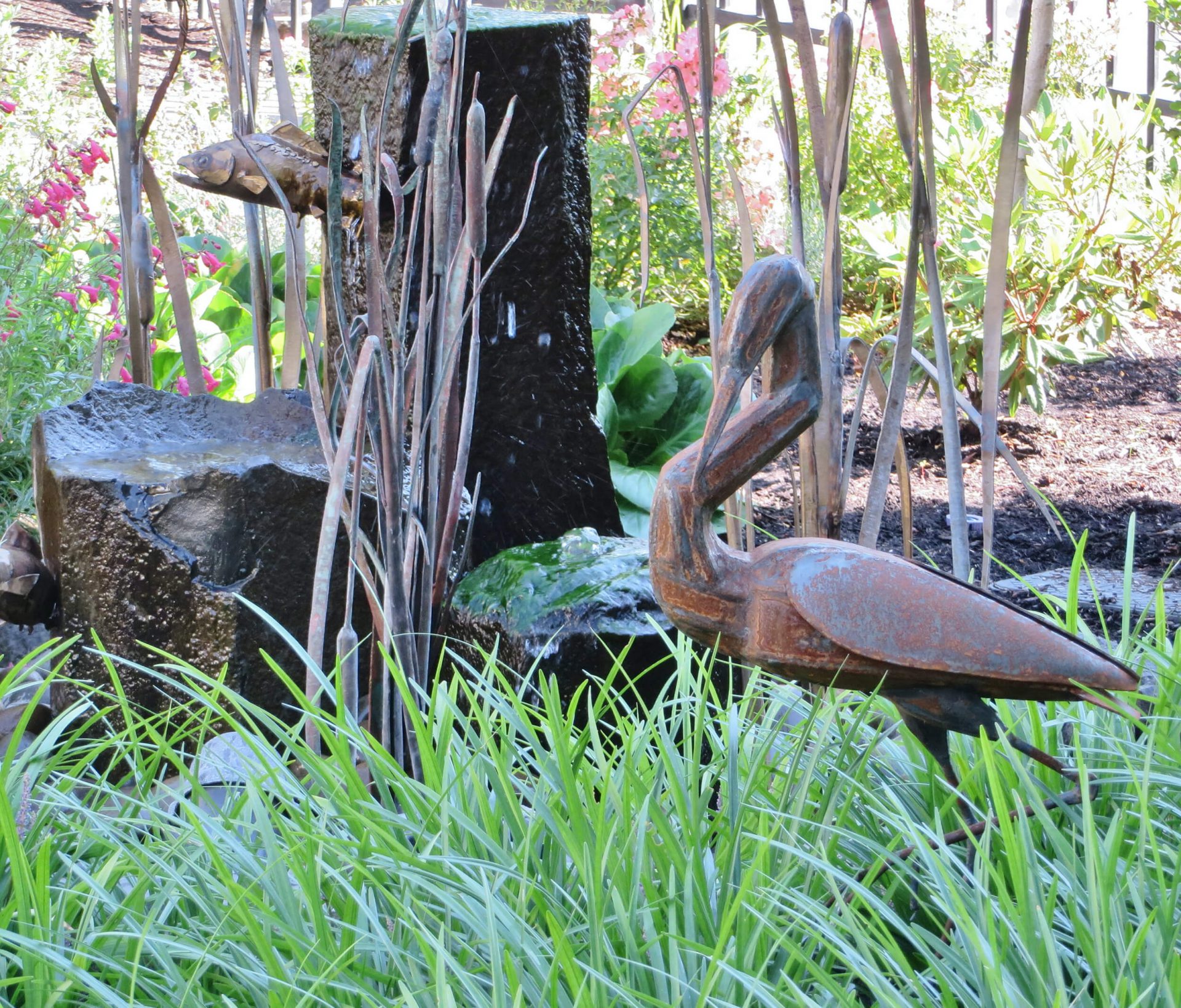 Statue of a blue heron in an outdoor campus garden.