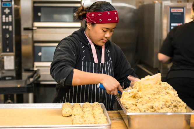 WV kitchen employee scoping chocolate chip cookie dough onto a baking sheet