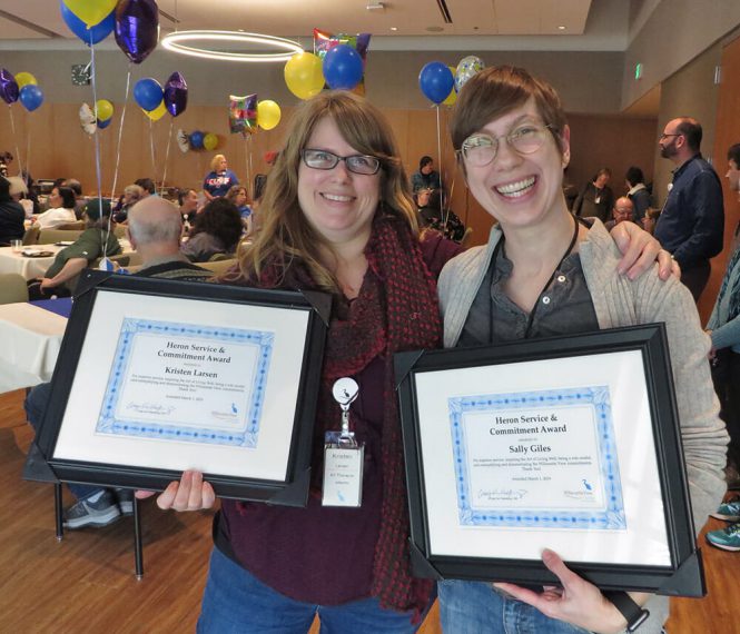 Two women showcasing their award certificates at an employee party