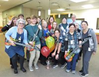 Large group of Willamette View employees posing with blow-up musical instruments and microphones.