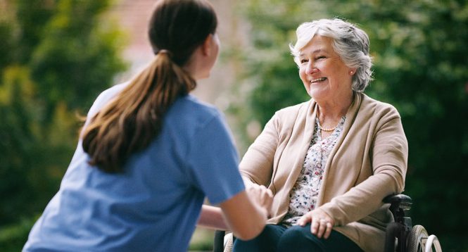 A healthcare worker engaging with a woman in a wheelchair