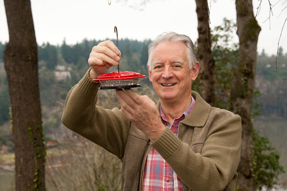A man highlighting a bird feeder he made