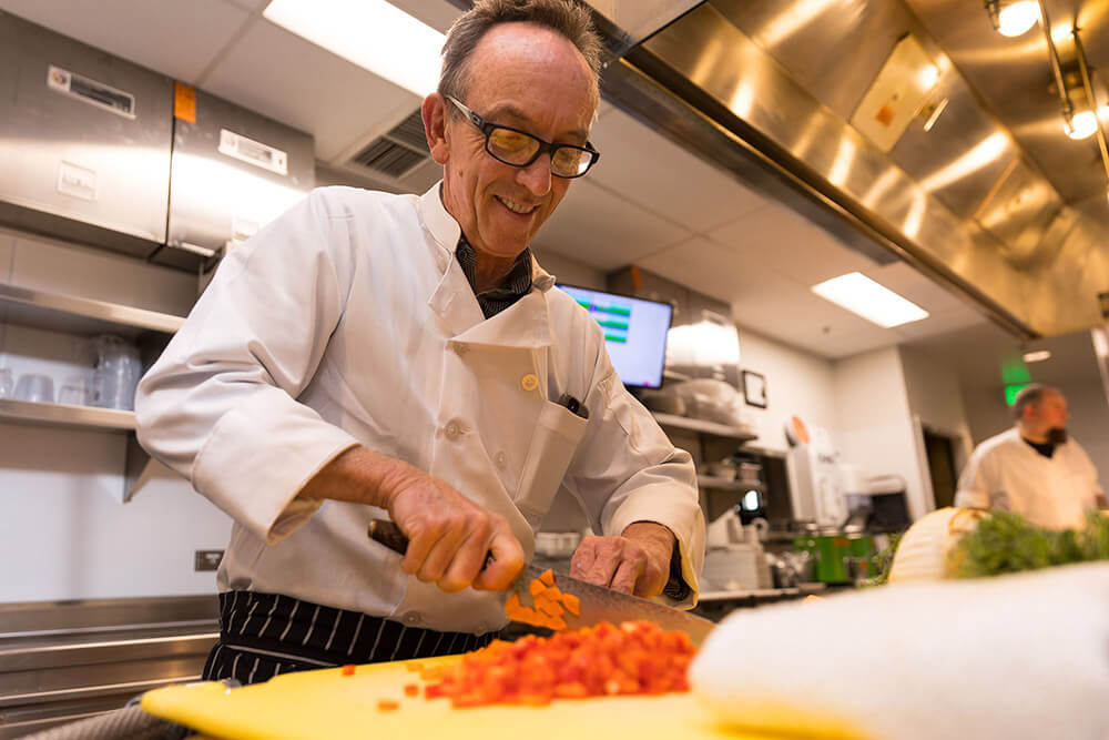 Willamette View executive chef cutting bell peppers and carrots in the kitchen