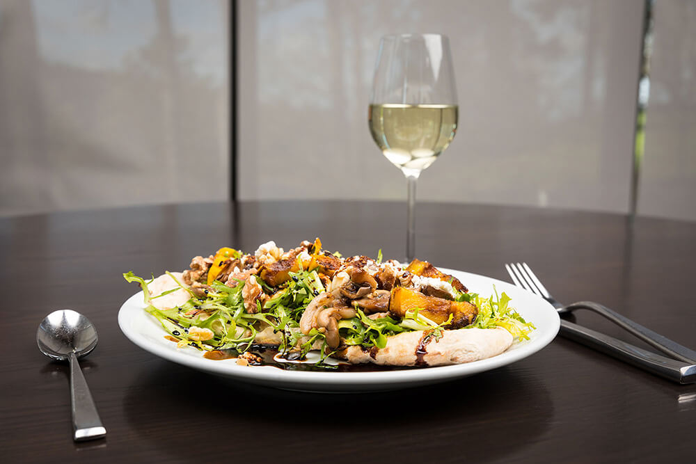 A mushroom flatbread dish with a vinegar sauce and a glass of white wine