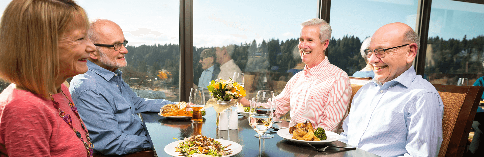 Two couples in the Riverview dining room enjoying food and the view of the river