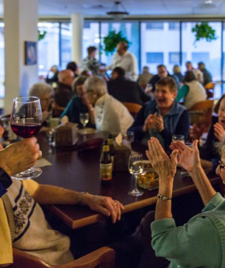 An active dining event at Willamette view with a woman holding a glass of wine in the foreground