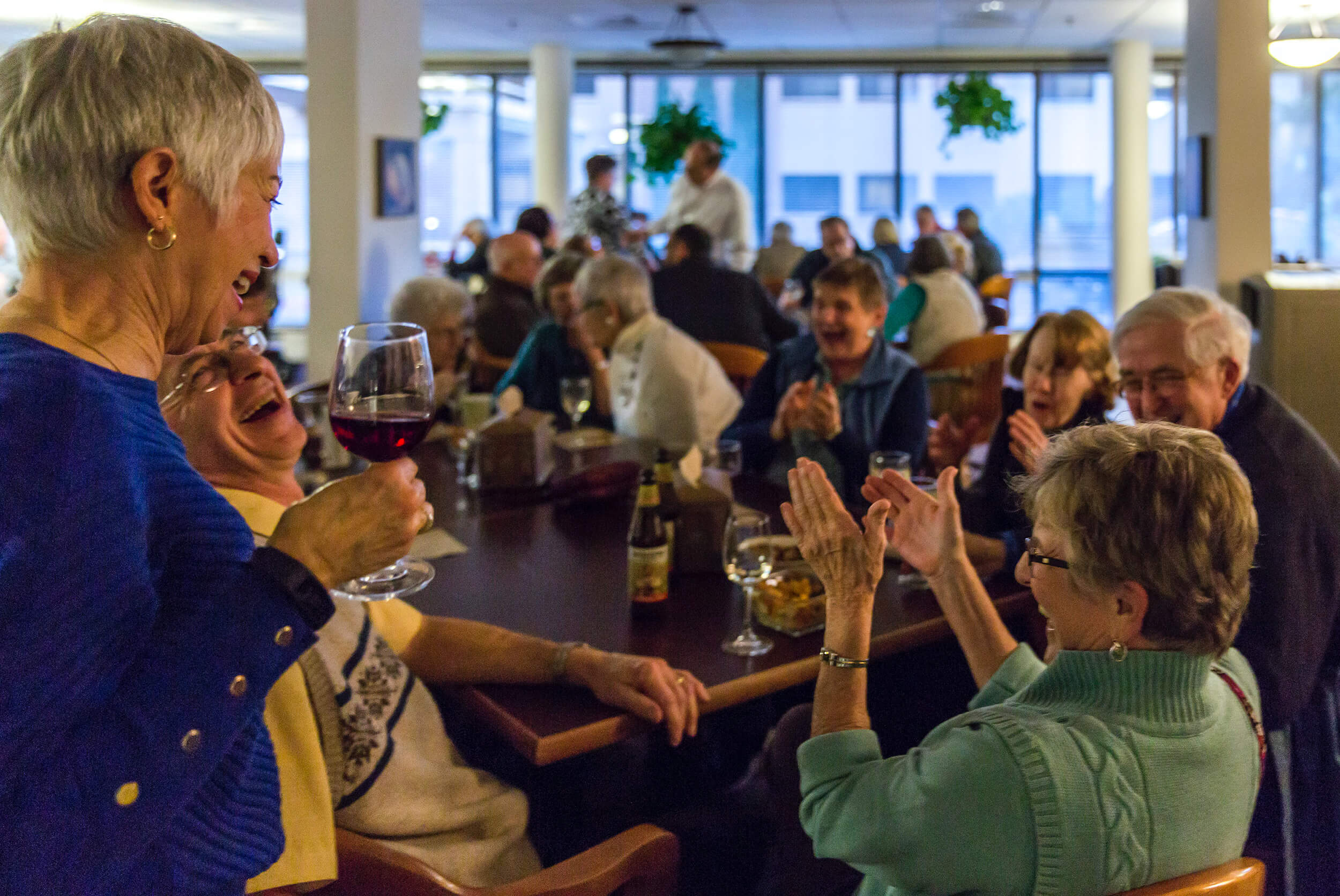 An active dining event at Willamette view with a woman holding a glass of wine in the foreground