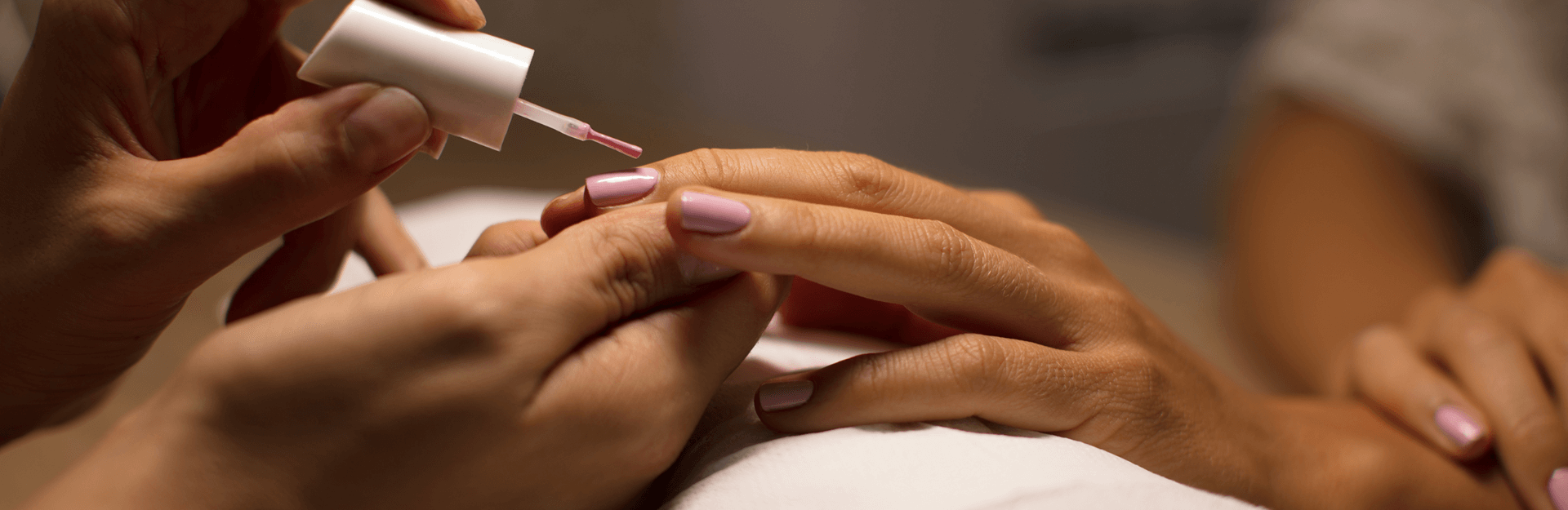 Close up of a manicure with pink nail polish being applied