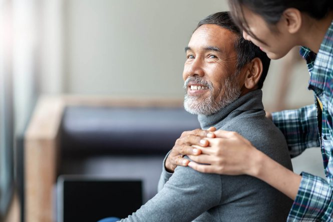 Portrait of a man in a wheelchair with a healthcare worker assisting him