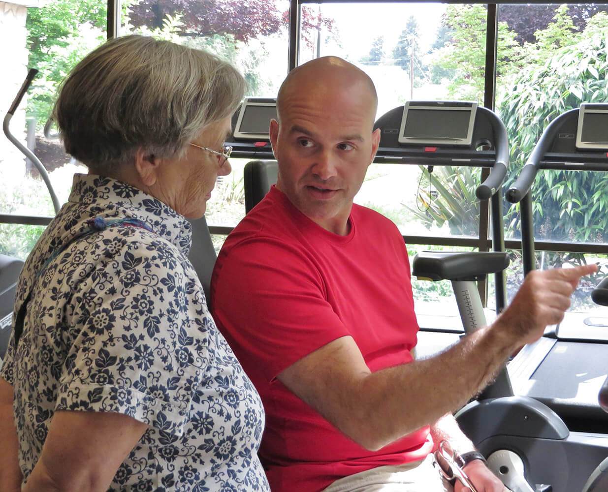 The Willamette View trainer showing a woman how to use the fitness equipment
