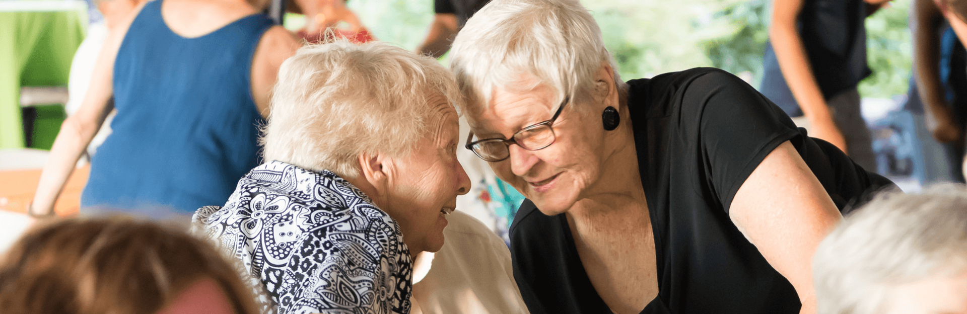 Two women getting close together so they can talk to each other at a party