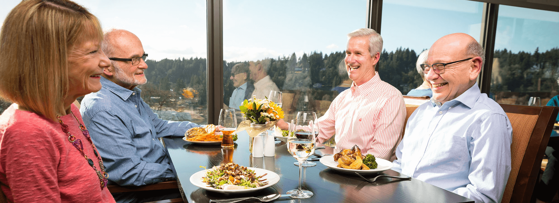 Two couples in the Riverview dining room enjoying food and the view of the river