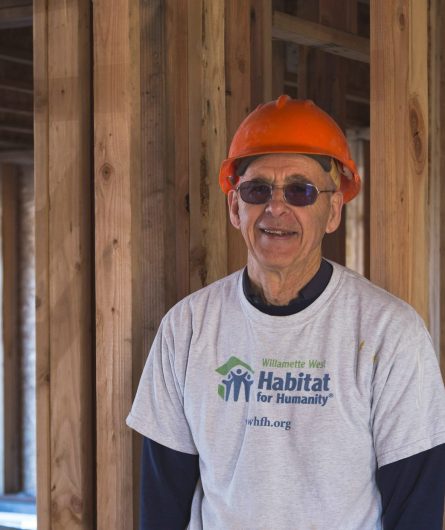 Cliff is at a Habitat for Humanity construction site with a hard hat on