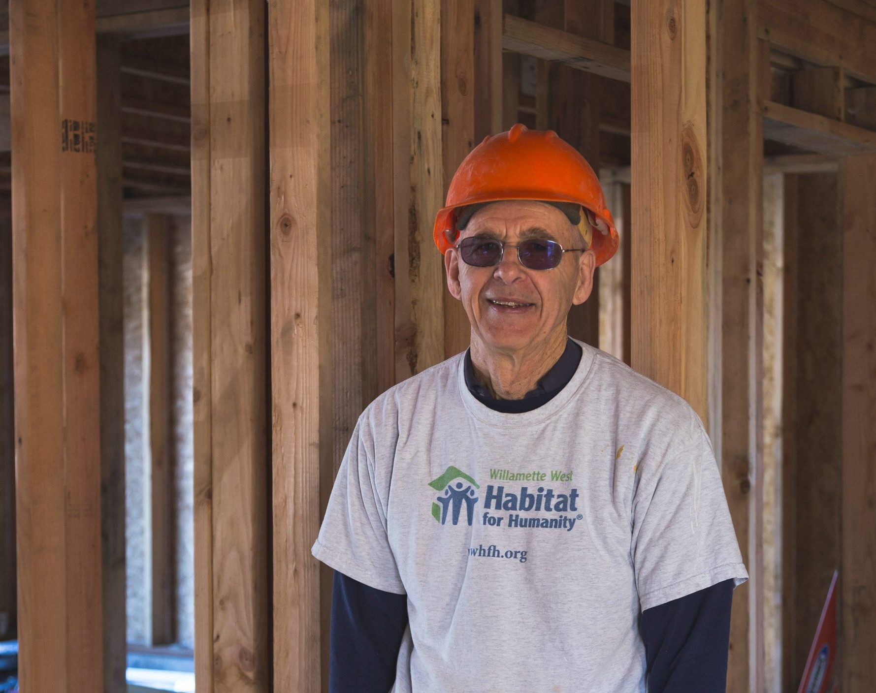 Cliff is at a Habitat for Humanity construction site with a hard hat on