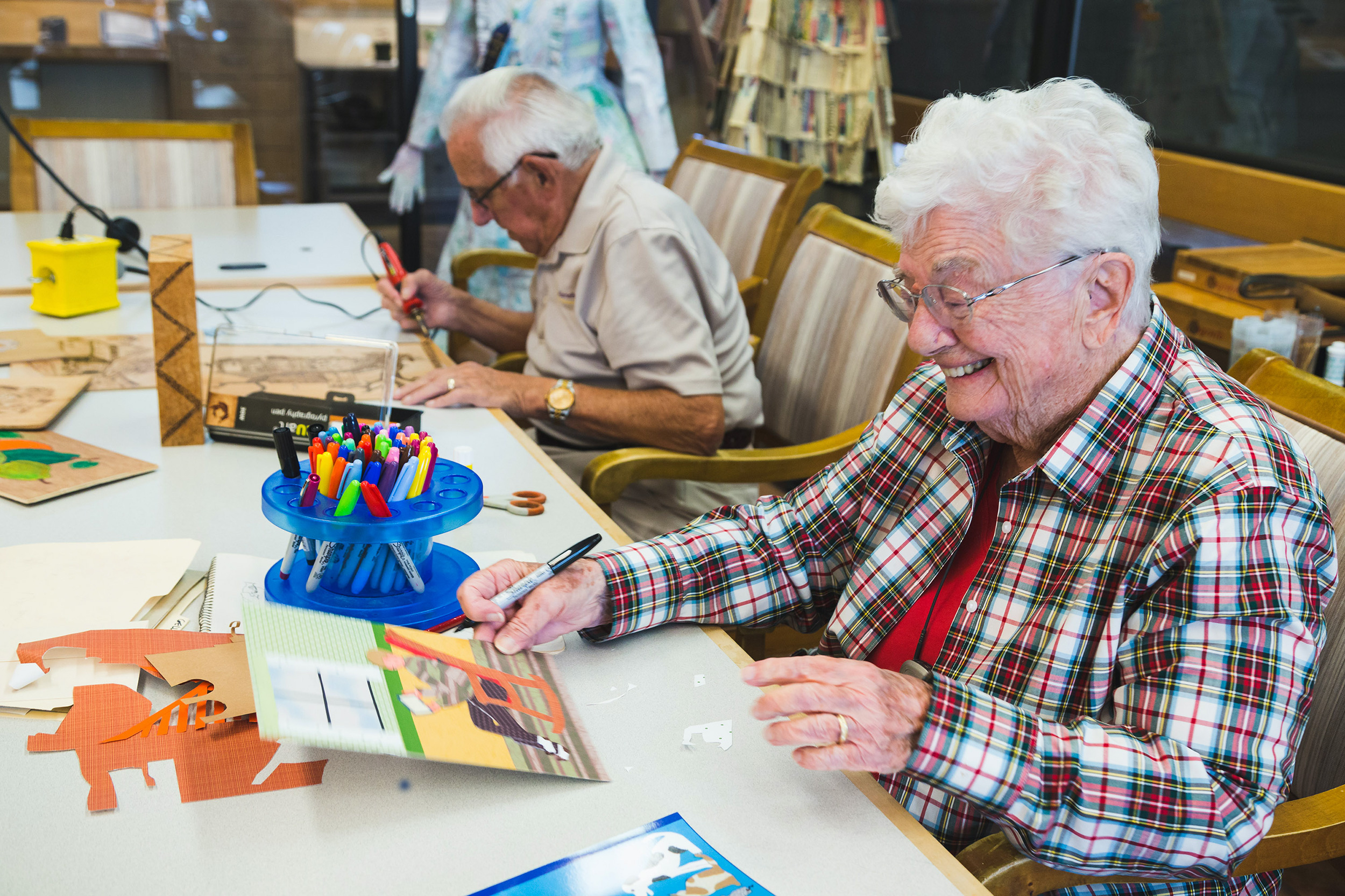 An art class were residents are drawing, painting and wood burning on wood panels